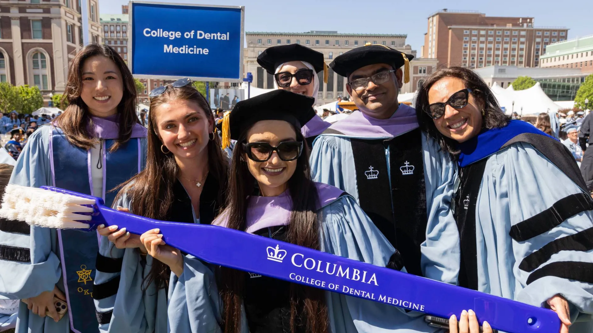 Graduates with a College of Dental Medicine sign at Commencement by Lucas Hoeffel.
