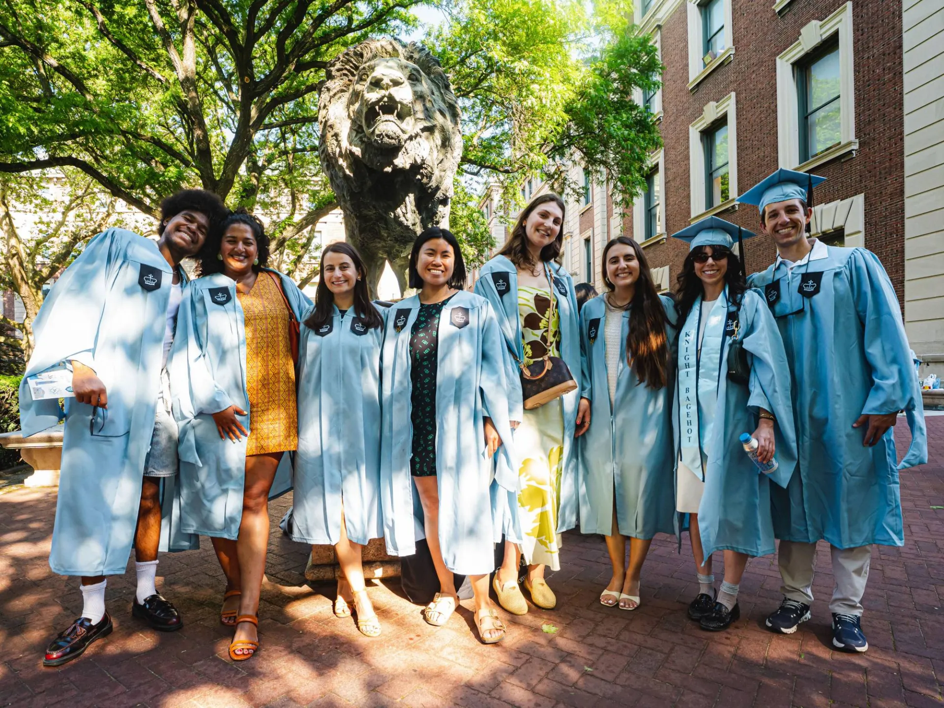 Smiling graduates at the lion statue. Image by Brandon Vallejo.