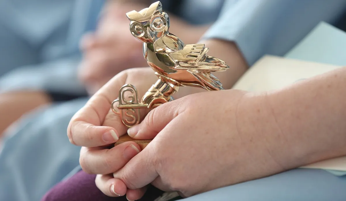 Graduating student holding General Studies owl statue
