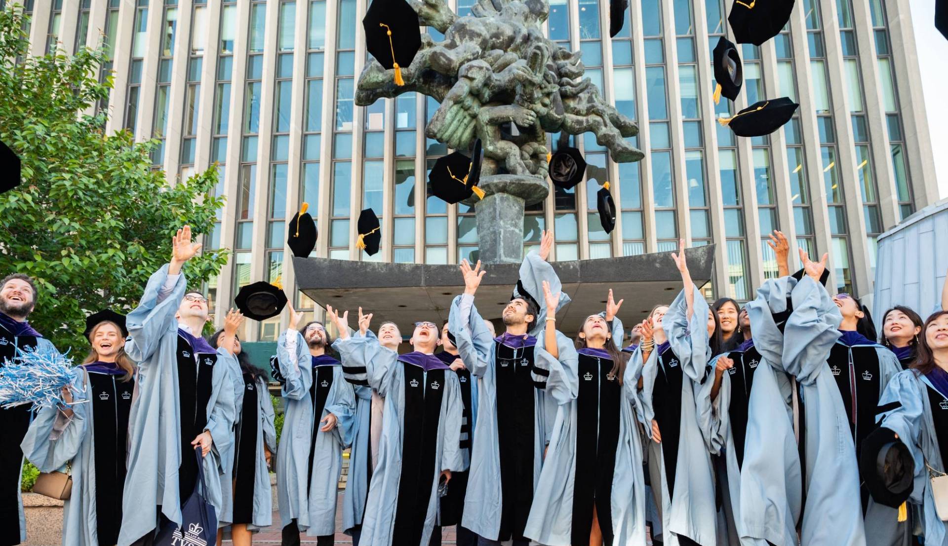 Columbian doctoral graduates throwing their mortarboards in the air in celebration at University Commencement.