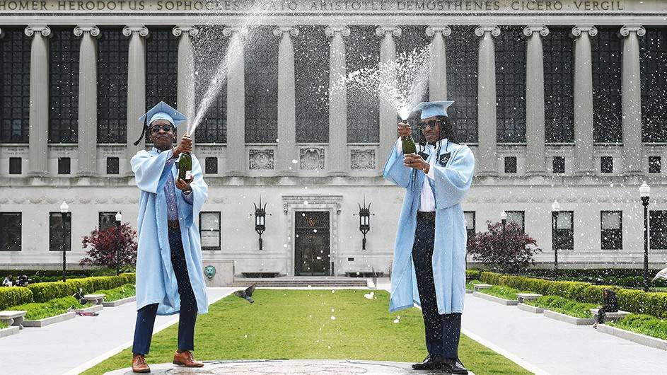 Two Columbia grads popping champagne bottles in front of Butler library