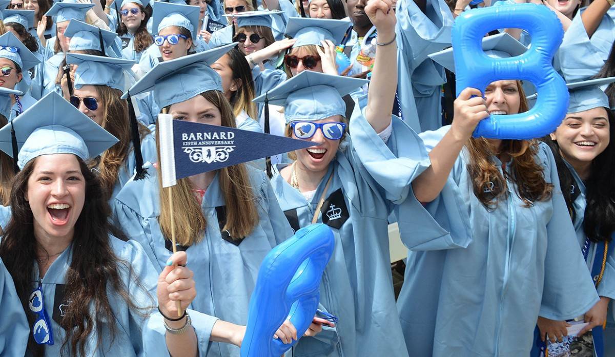 Graduating students holding Barnard signs during commencement ceremony